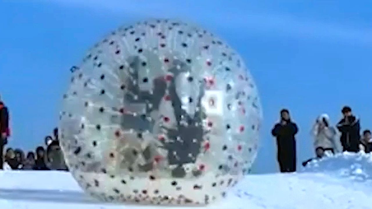Video: Schwindelerregend: Touristen rollen im Riesenball die Piste runter